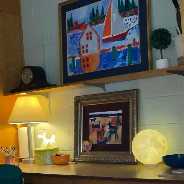 A Hugentobler3D moon lamp glowing on a shelf beside framed artwork and a table lamp