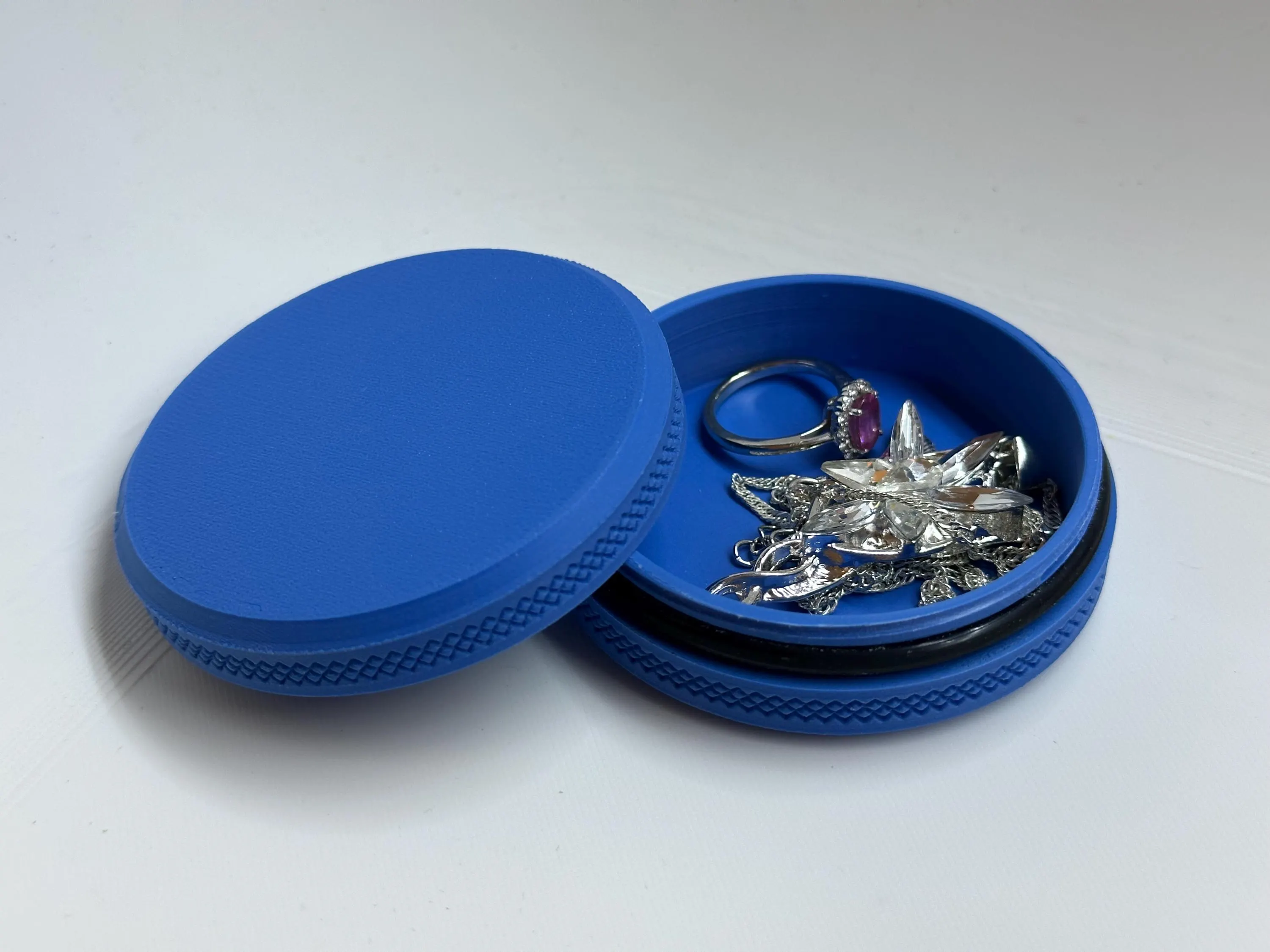 Open blue twist tin holding a silver ring and a crystal pendant